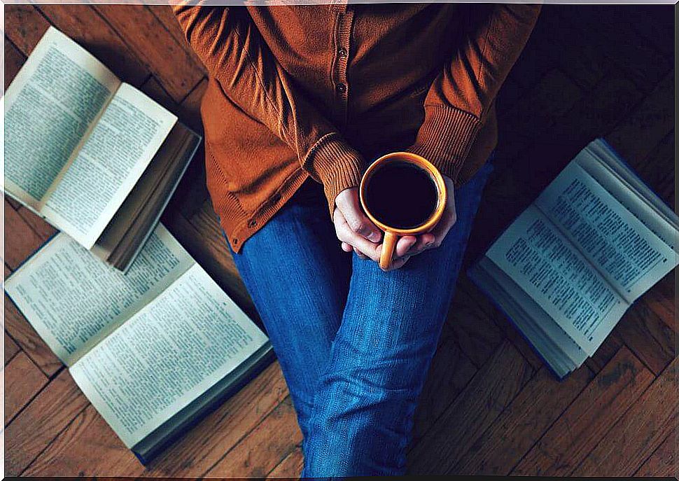 Woman drinking coffee surrounded by books