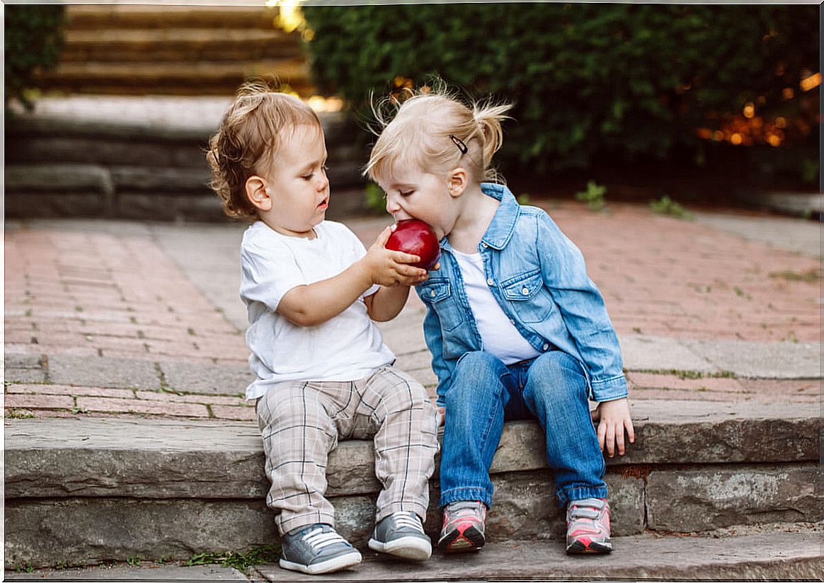 Little boy giving an apple to another girl