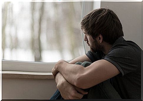 Sad man looking out the window in autumn