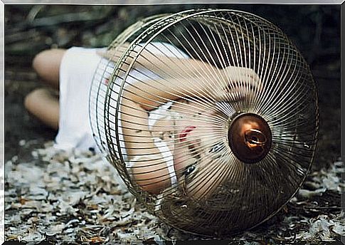 Woman locked in a cage lying on the ground