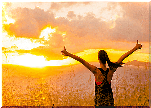 Woman with arms up at sunrise