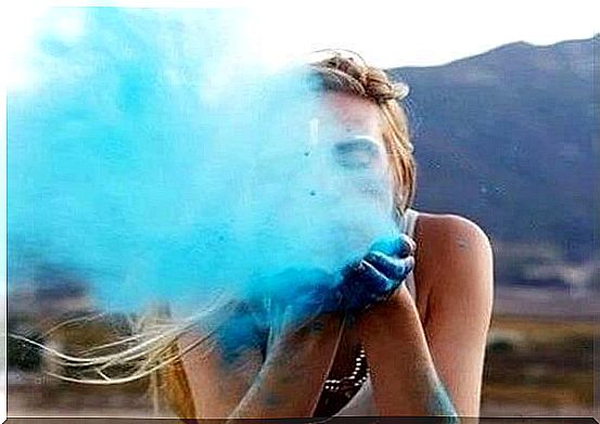 girl blowing blue sand